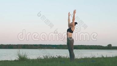 日出时做瑜伽的女人。 瑜伽、运动和健康生活方式概念